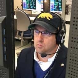 Mark Lewis looking at a monitor with a headset on