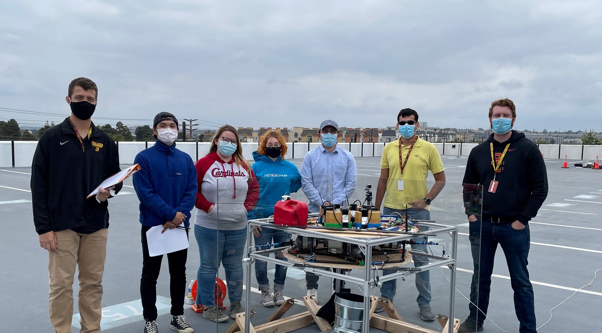 seven people standing around a table with a project on top