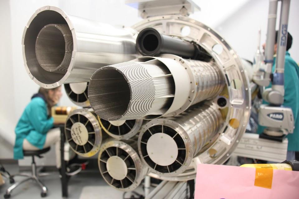 Foxi rocket being built, in the background two scientists wearing green lab coats are working